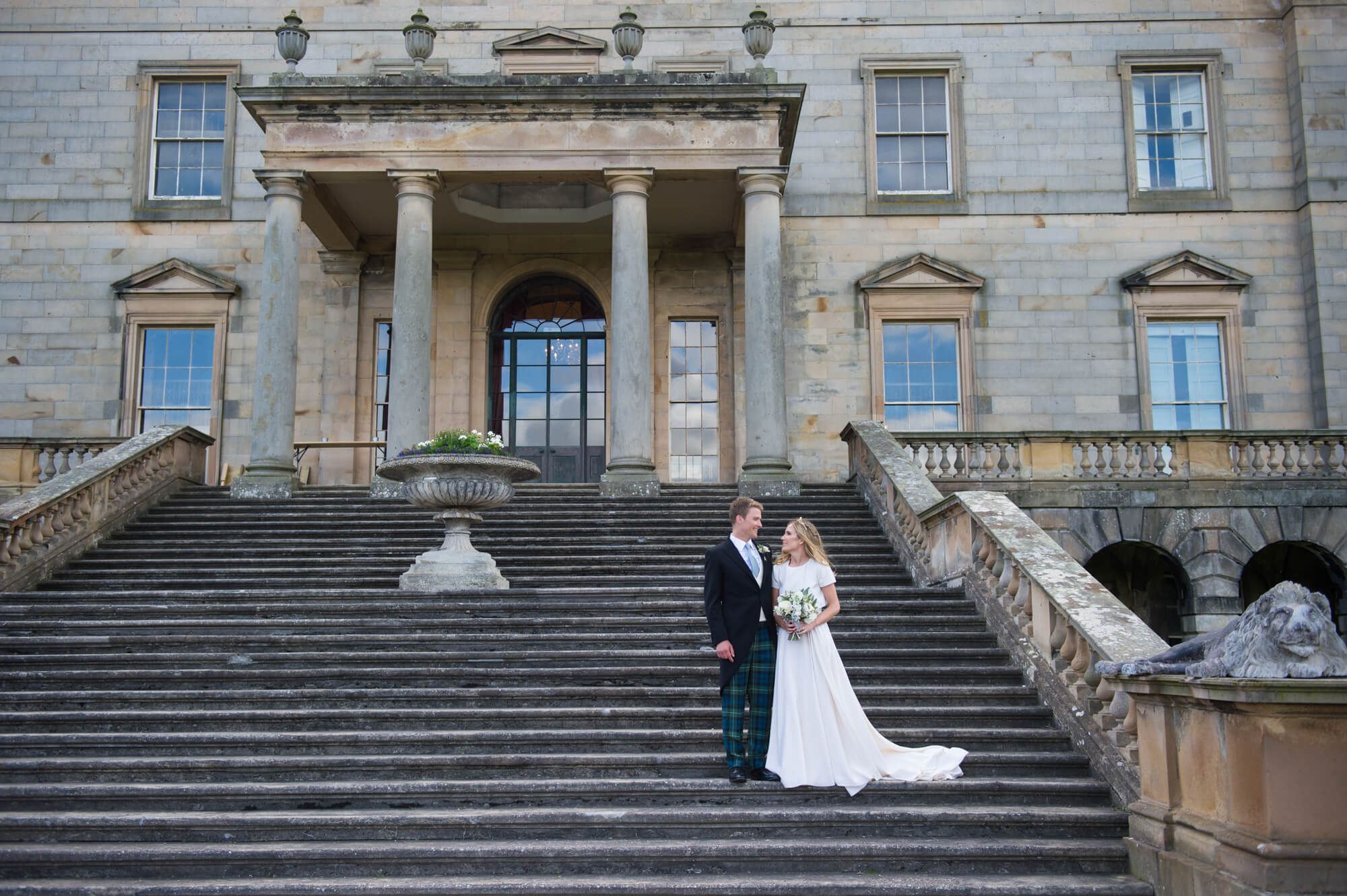 A couple on their wedding day on the steps of Godford House in Scotland